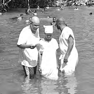 A baptism in a river, with two brothers standing beside the candidate